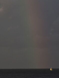 Un velero iluminado por un arcoíris